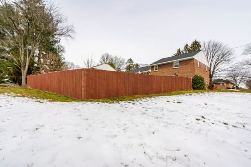 Brick home exterior with a new wood deck, string lights and a snow-patched lawn