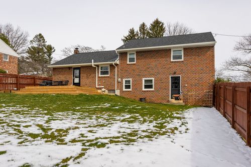 Brick home rear exterior with a freshly built wood deck and privacy fencing