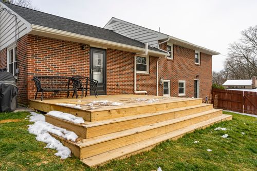 New wood deck steps leading up to a brick home's back entrance