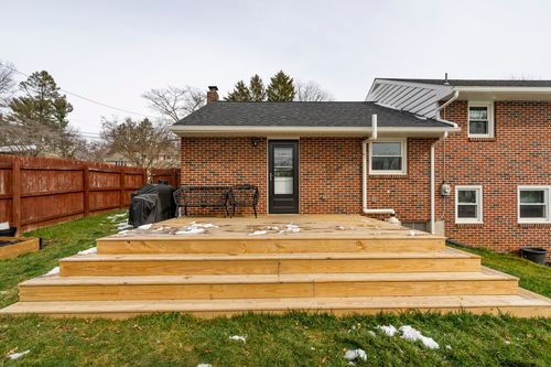 Wood deck and steps against a brick home exterior with wood privacy fence