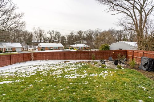 Fenced backyard with a stacked-stone fire pit, patio seating and snow patches