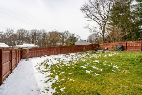 Snow-dusted backyard framed by a tall wood privacy fence