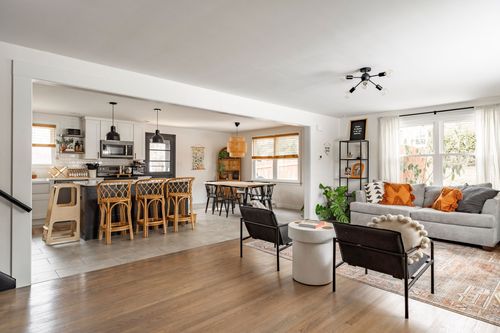 Open-concept living room and kitchen with wood floors and rattan bar stools