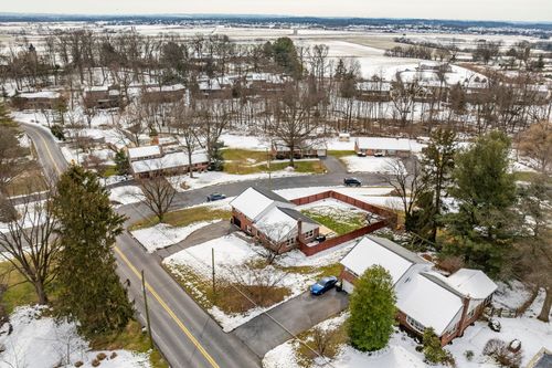 Aerial winter view of a neighborhood with brick homes, a parking lot and open farmland