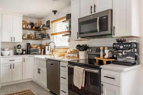 White kitchen with dark island, subway tile backsplash and open wood shelving