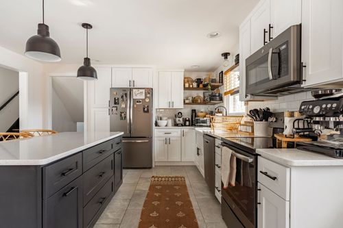 White kitchen with stainless appliances, farmhouse sink and open shelving