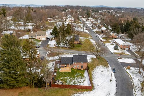 Aerial winter view of a brick home along a tree-lined residential street