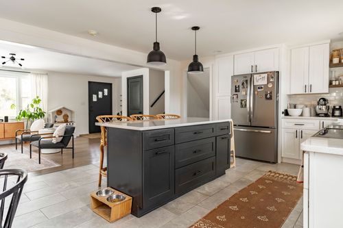 White kitchen with black island, runner rug and stainless range