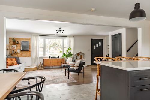 Open kitchen and living area with black island, pendant lights and staircase