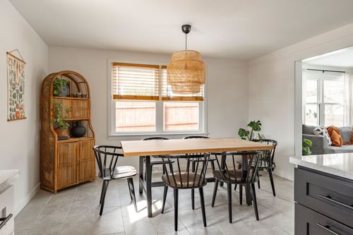 Dining nook with wicker cabinet, woven pendant light and black windsor chairs