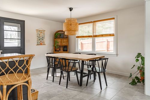 Dining area with wood table, black chairs and a woven pendant light fixture