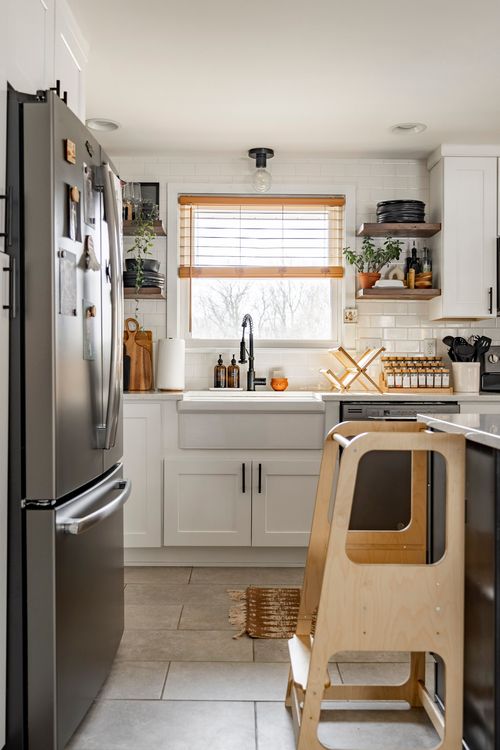 White kitchen with stainless refrigerator, subway tile backsplash and bamboo shade
