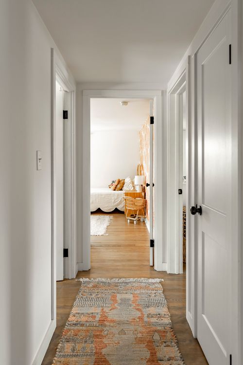 Hallway with white doors, wood floors and a patterned runner rug
