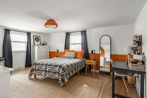 Kids bedroom with orange dome pendant light and black-and-white geometric bedding