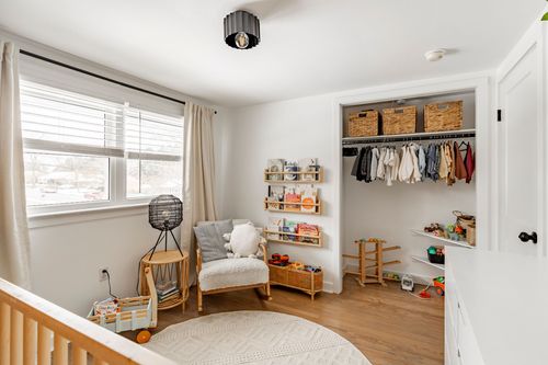 Kids bedroom with an organized closet, gray upholstered chair and round rug