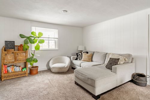 Finished basement family room with a light gray sectional sofa and houseplant