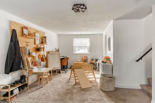 Basement mudroom with a wood pegboard wall, boot tray and kids play ramp