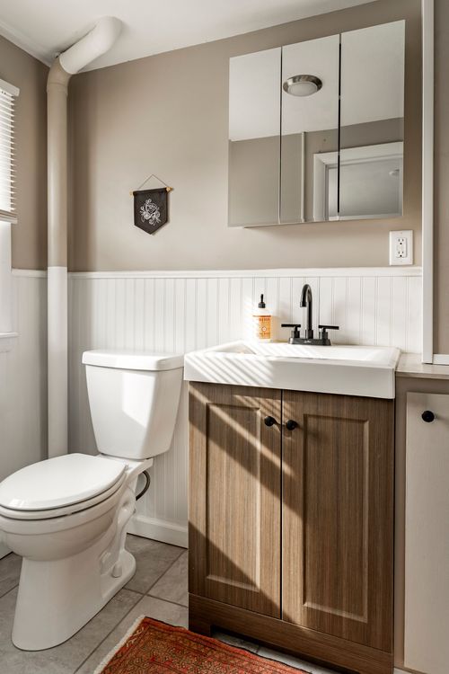 Bathroom with a wood-front vanity and a mirrored medicine cabinet with sconce lighting