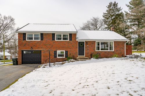 Brick split-level home entrance with black garage door and snow-covered driveway