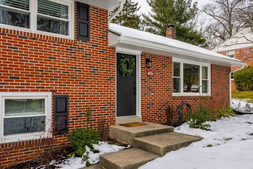 Tall wood privacy fence enclosing a snow-dusted backyard beside a brick home