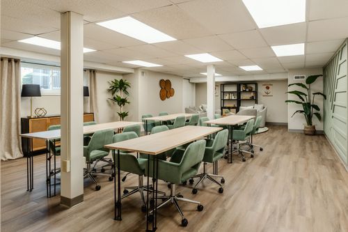 Basement conference room set with rows of long tables and green upholstered chairs