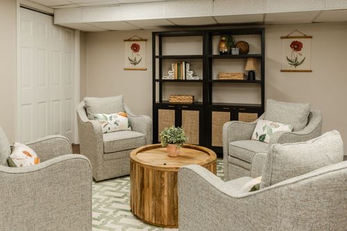 Lounge seating area with four neutral swivel chairs around a round wood coffee table