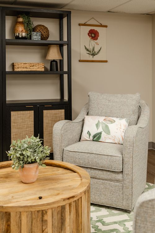 Close-up of a botanical art print above a black bookshelf beside a neutral chair
