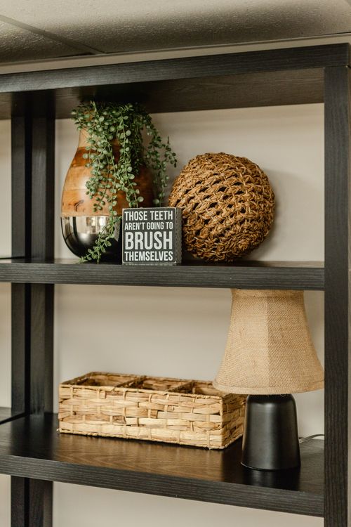 Close-up of styled shelf decor with a woven ball, dental-themed sign and table lamp