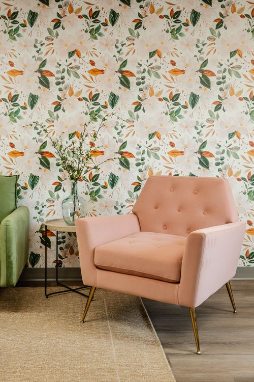 Close-up of a round wood coffee table beside a green sofa and pink armchair