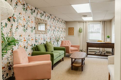 Waiting room seating with a desk and office chair visible near a sunlit window