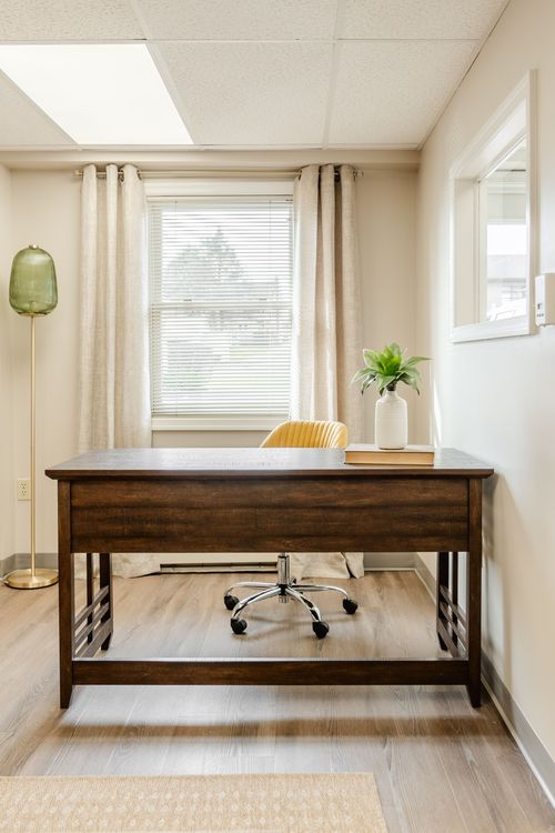 Private office with a dark wood desk, mustard upholstered chair and floor lamp