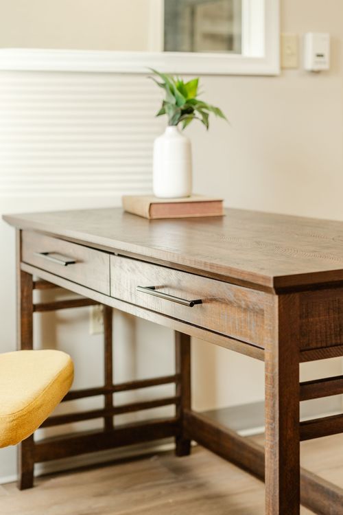Close-up of a dark wood desk drawer with a potted plant and book