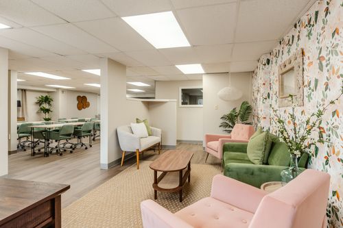 Open basement lounge and conference space with tables, chairs and floral wallpaper accent