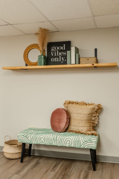 Close-up of a floating shelf styled with a mirror, vase and basket over an upholstered bench