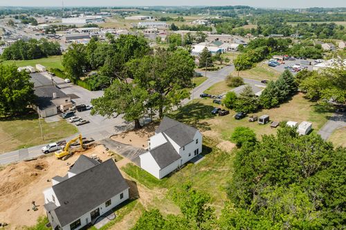Aerial view of new home construction near a small town with parked cars and trees