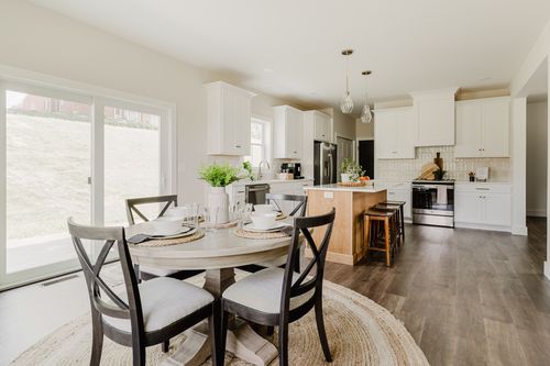 Open dining and kitchen area with a round table set for four near sliding glass doors