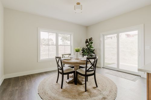 Dining nook with round table and chairs beside sliding glass doors to the yard
