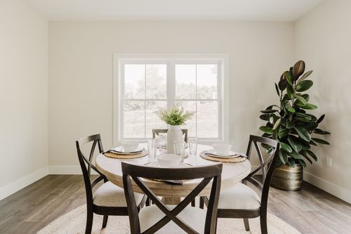 Dining room with a round wood table, cross-back chairs and a jute rug