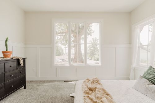 Bedroom corner with a dark wood dresser and a window framing a large tree