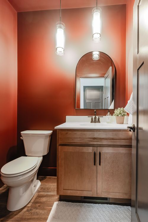 Terracotta powder room with pendant lighting, arched mirror and wood vanity
