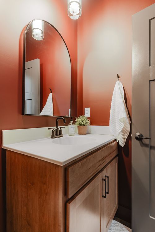 Terracotta powder room vanity with arched mirror and hanging towel