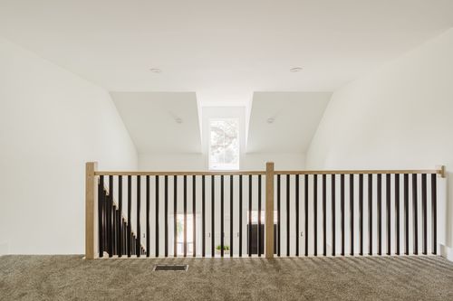 Loft landing with black stair railing, skylight and carpet flooring