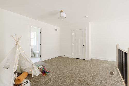 Empty bonus room with a play tent and a door to a bathroom