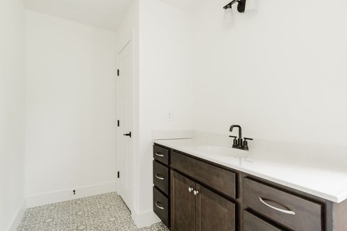 Dark wood vanity in an unfinished bathroom corner with patterned tile flooring