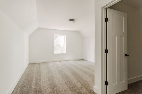 Unfinished sloped-ceiling bedroom with a single window