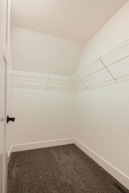 Empty walk-in closet with wire shelving beneath a sloped ceiling