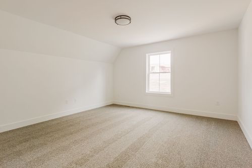 Unfinished bedroom with a single window and sloped ceiling
