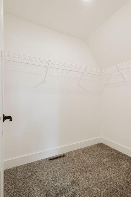 Empty walk-in closet with wire shelving and carpet flooring