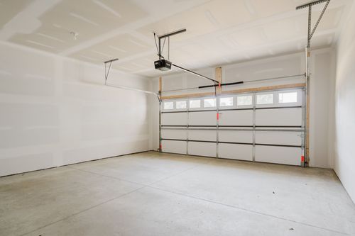 Empty two-car garage with an automatic opener and a window-paneled door