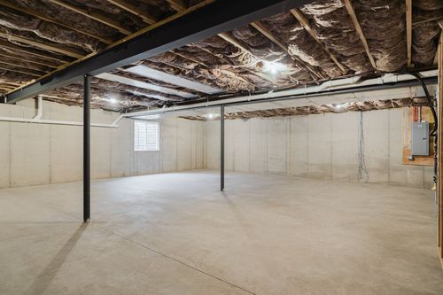 Unfinished basement with exposed floor joists and a steel support beam